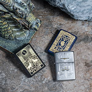 Three Medieval Inspired Designs lighters, laying on a stone surface with a dragon statue
