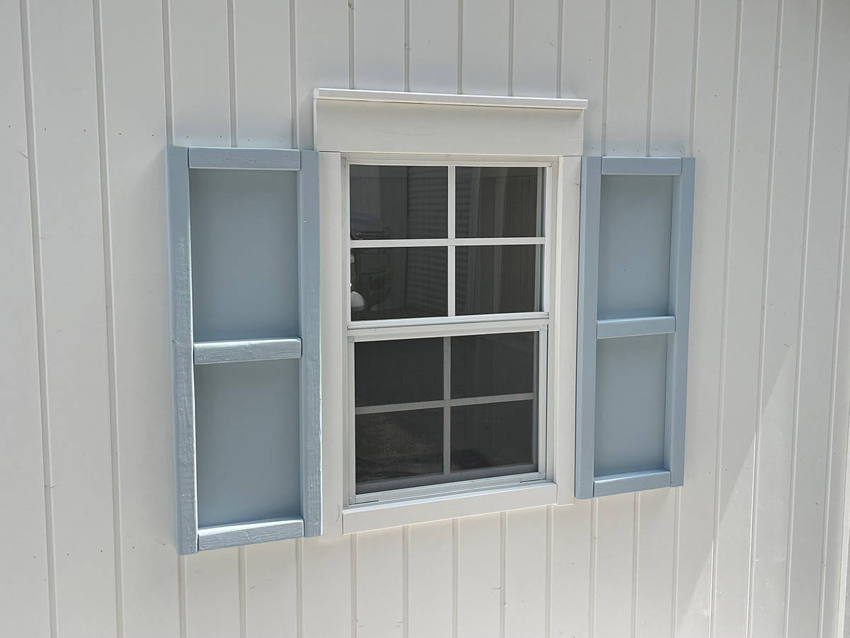 Close up of the functional Window with blue shutters of Custom Outdoor Playhouse by WholeWoodPlayhouses