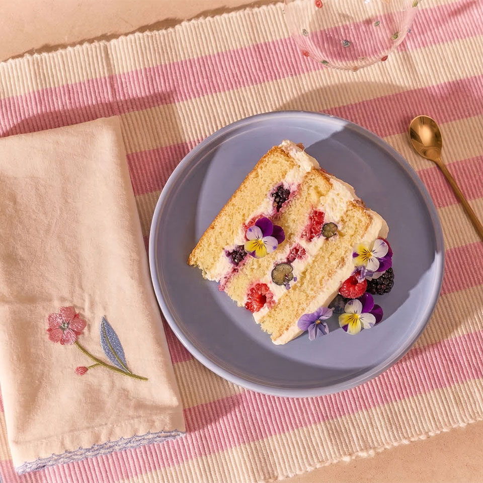 A slice of decorated cake on a blue plate with a napkin.