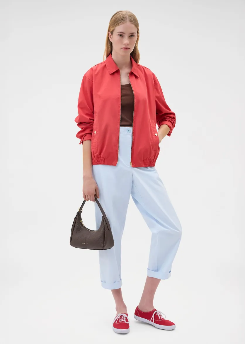 Person wearing a red jacket, brown top, light blue pants, and red shoes.