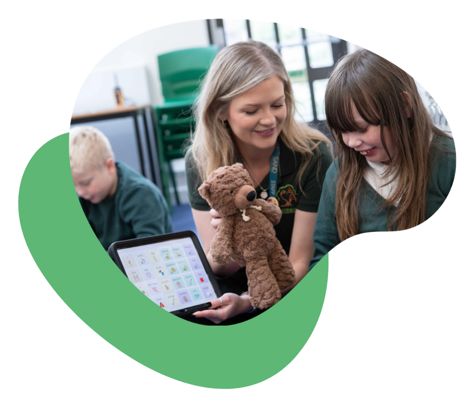 A teacher interacts with students using a tablet and a stuffed animal.
