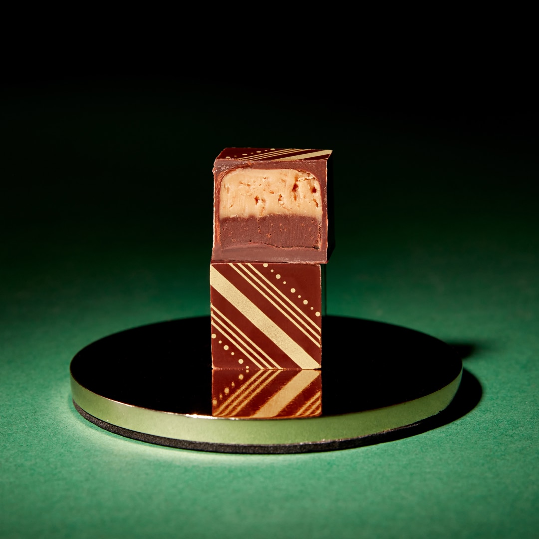 A chocolate piece with a decorative design on a circular stand.