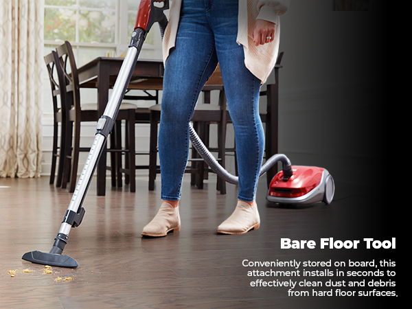 Person using a vacuum cleaner on hardwood floor with furniture in background.
