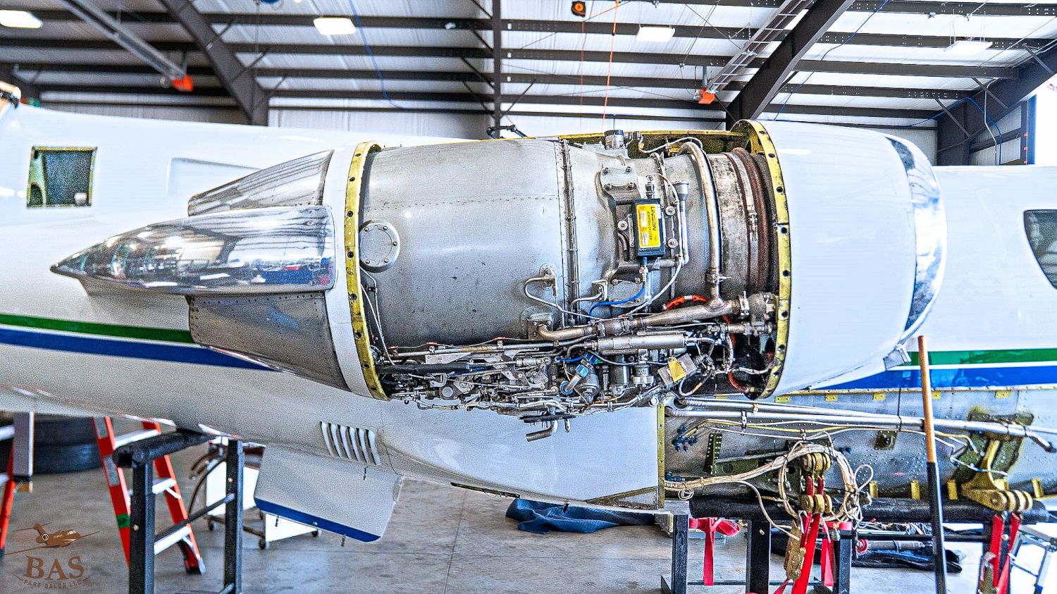 Jet engine partially disassembled inside an aircraft maintenance hangar.
