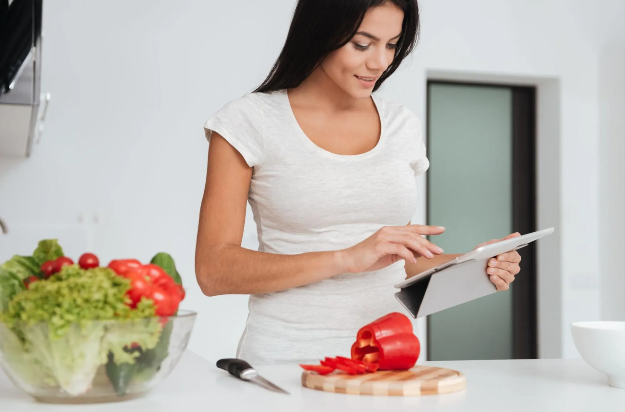 woman looking at recipe on iPad cutting veggies 