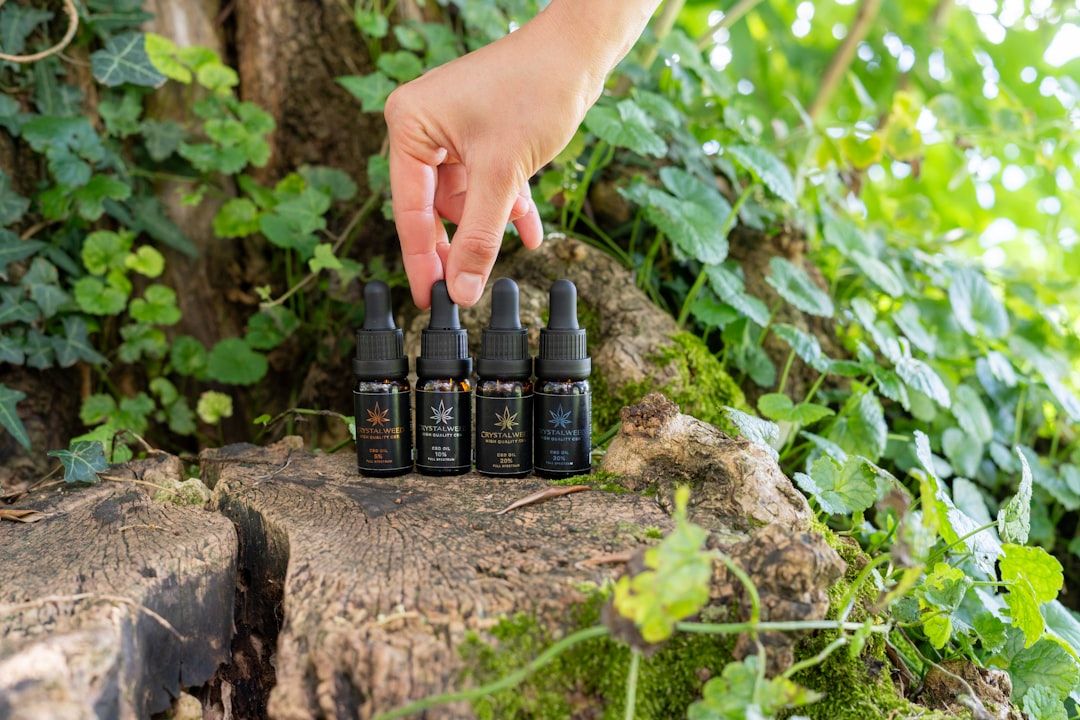 Hand places bottles on a tree trunk.