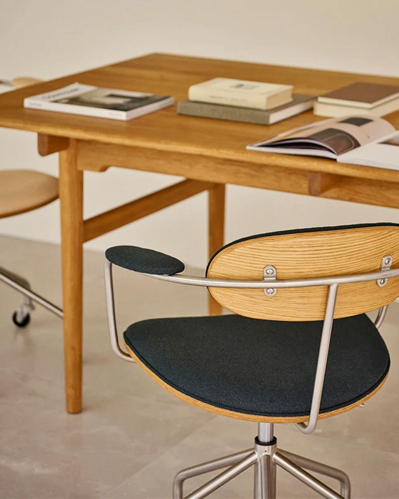 Wooden Carl Hansen table with books and modern chairs in a minimalist setting.