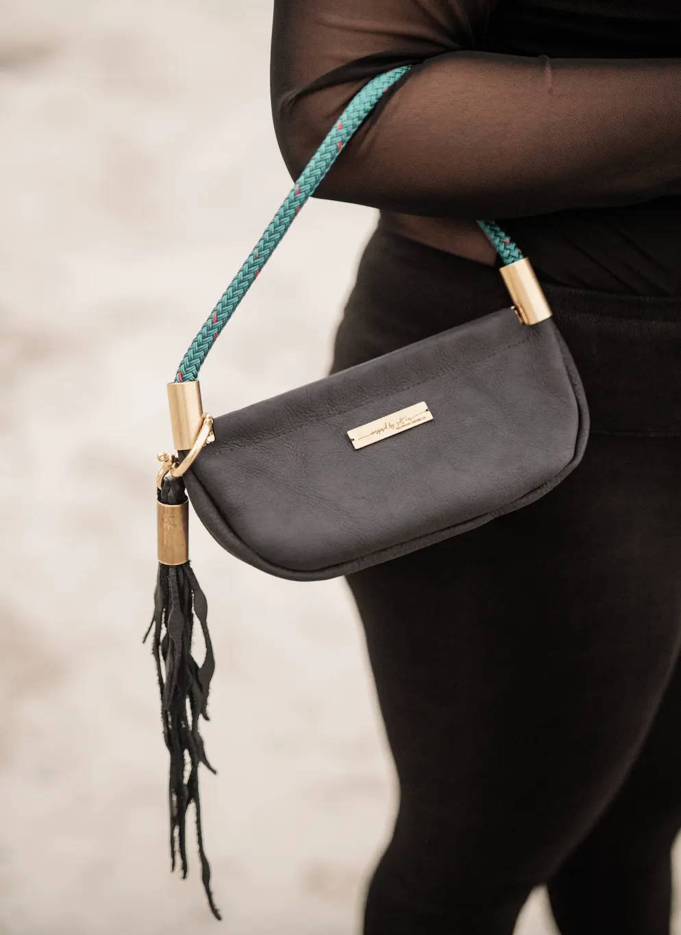 black leather bag with brass hardware and teal rope