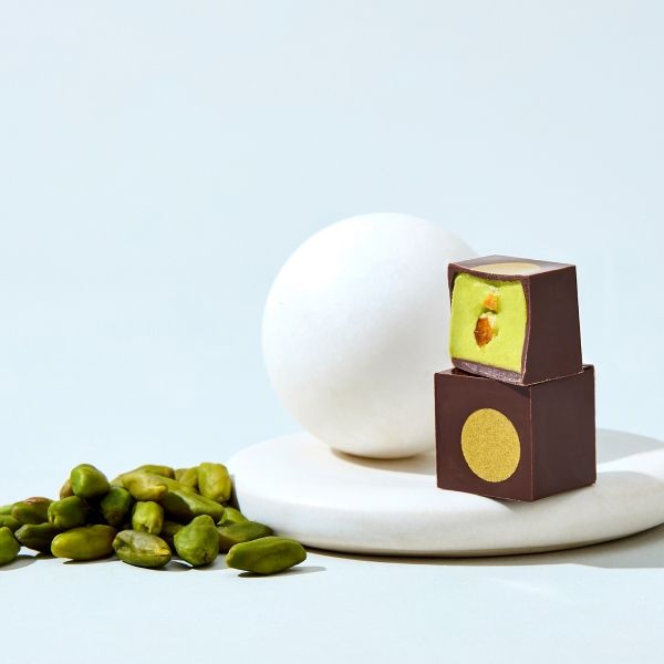 Chocolate candies with pistachios and a white egg on a plate.