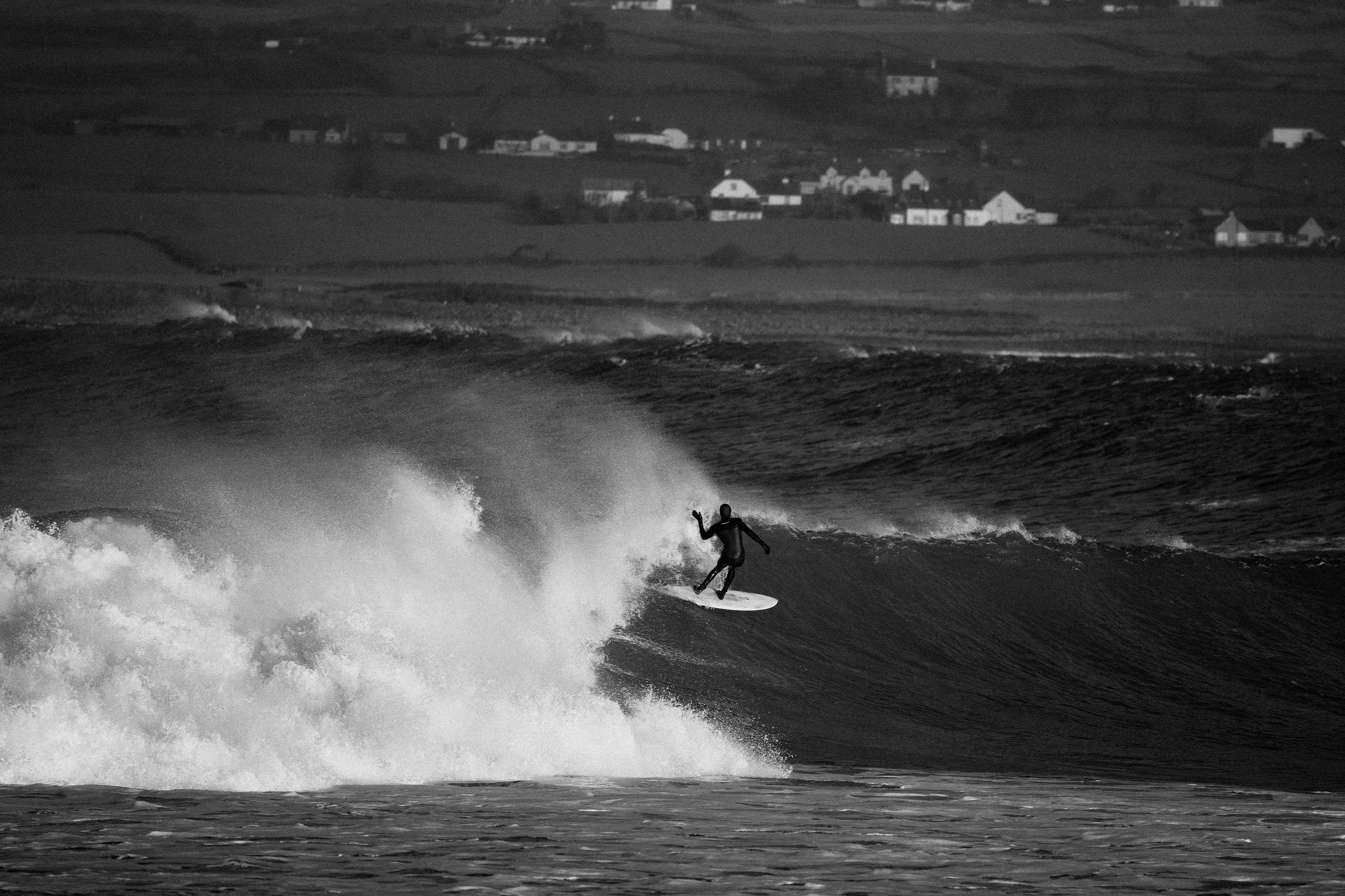 Surfer riding a wave in black and white ocean scene.