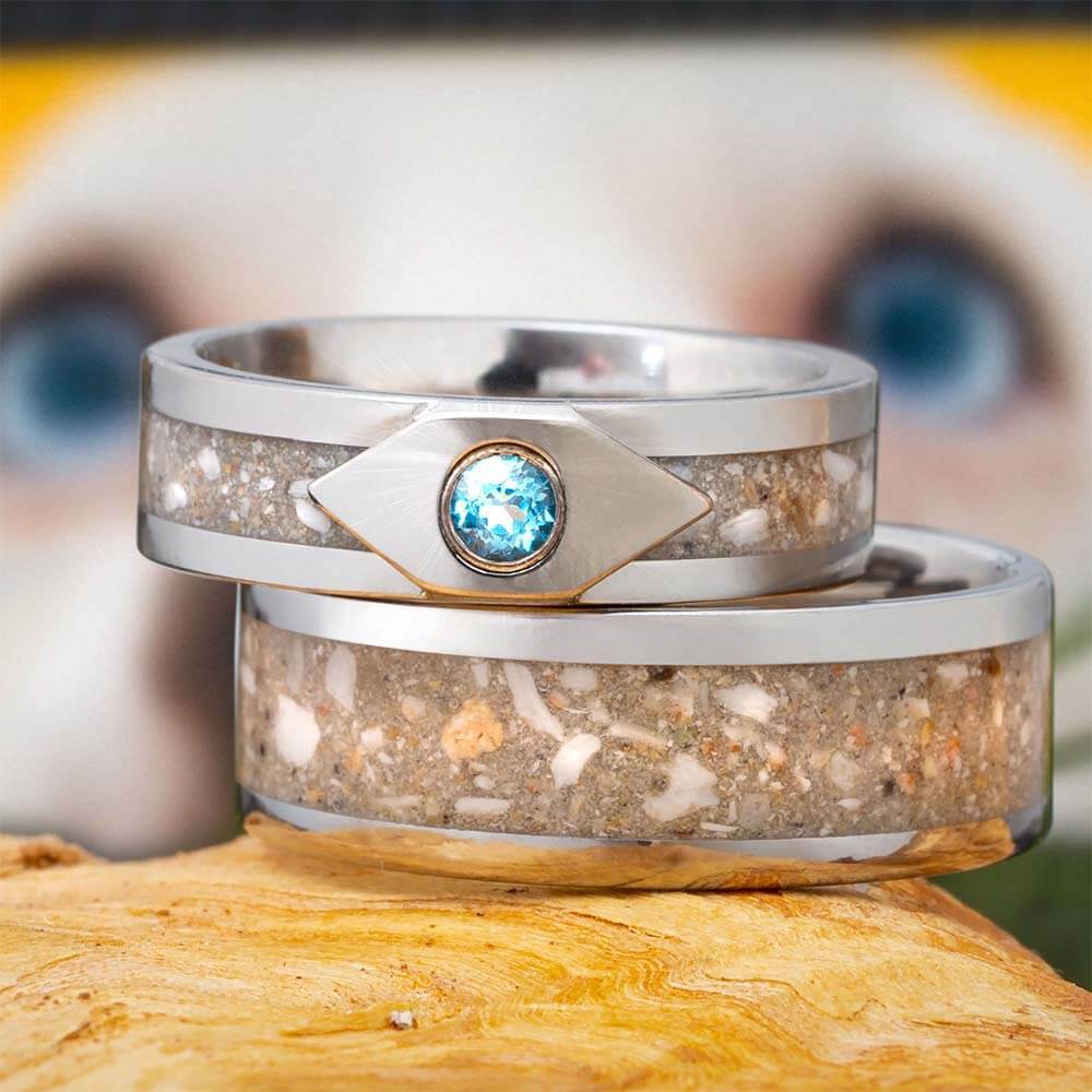 Two unique pet memorial rings on a wooden surface, featuring a blue gemstone.