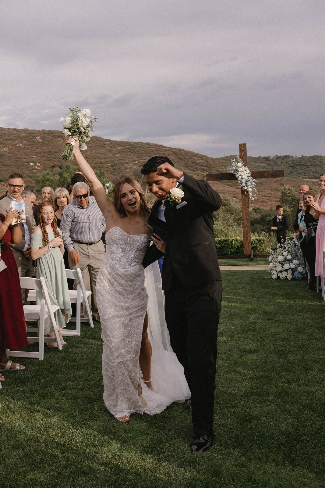 Bride and groom celebrating after wedding ceremony in outdoor setting.