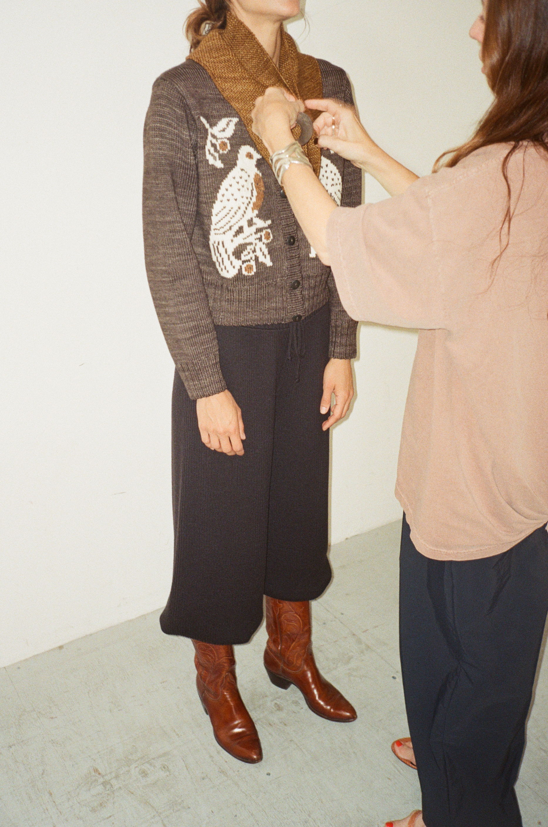 Person adjusting clothing on another person in a fashion setting.