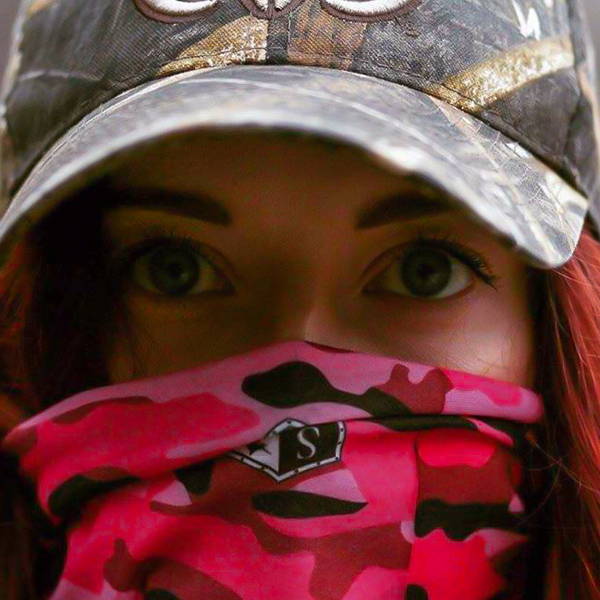 Shannon Wolff starring into the camera while wearing a pink camo face shield over her face and a hat.