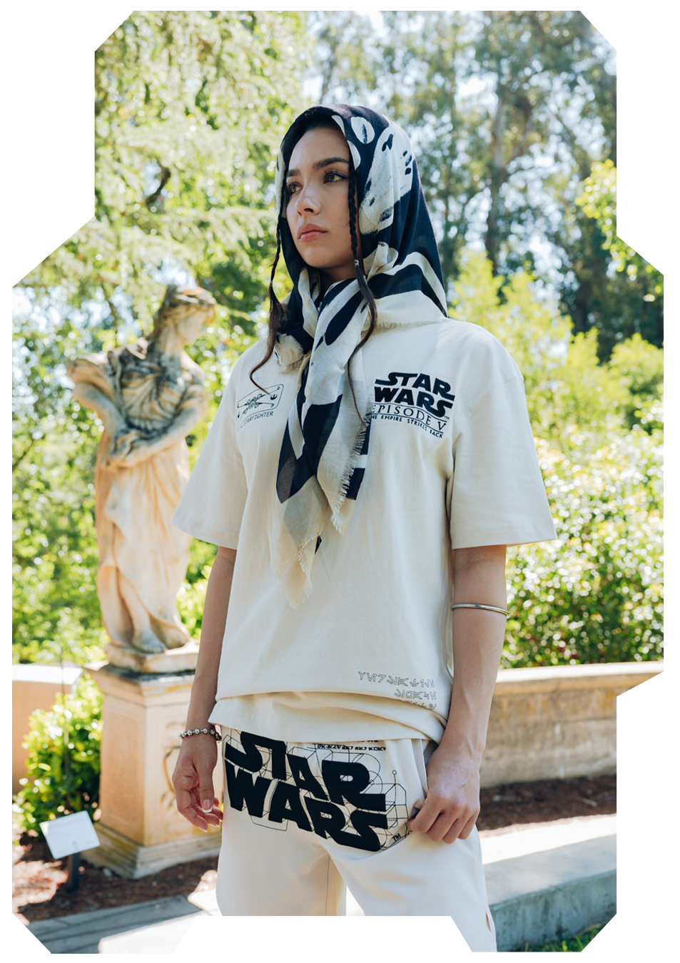 Person wearing Star Wars apparel and a patterned scarf in a garden setting.