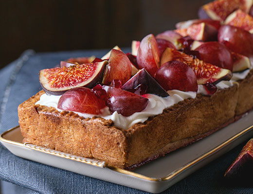 A dessert with cream and fresh figs on a rectangular cake.