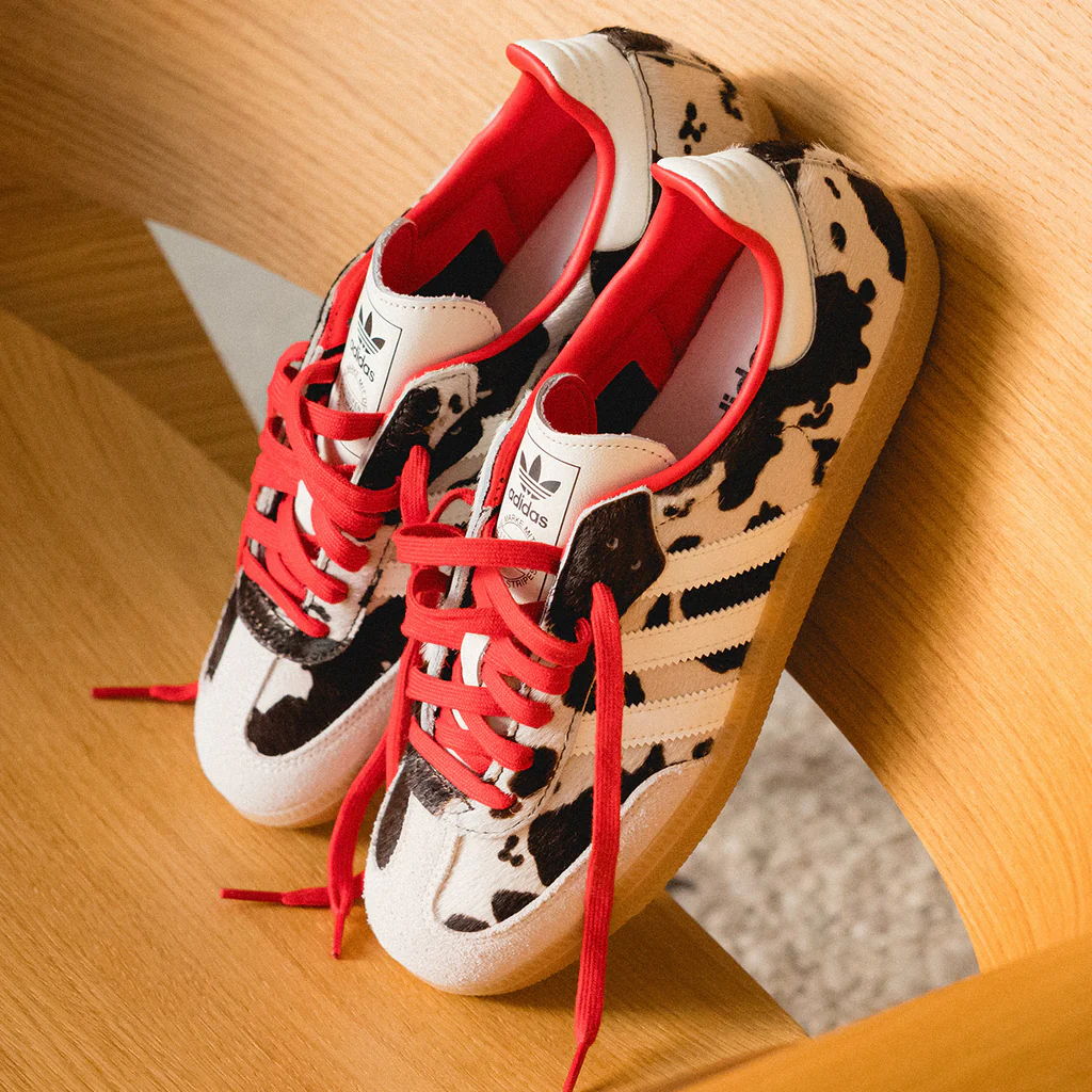 A pair of stylish sneakers with a cow print and red laces.