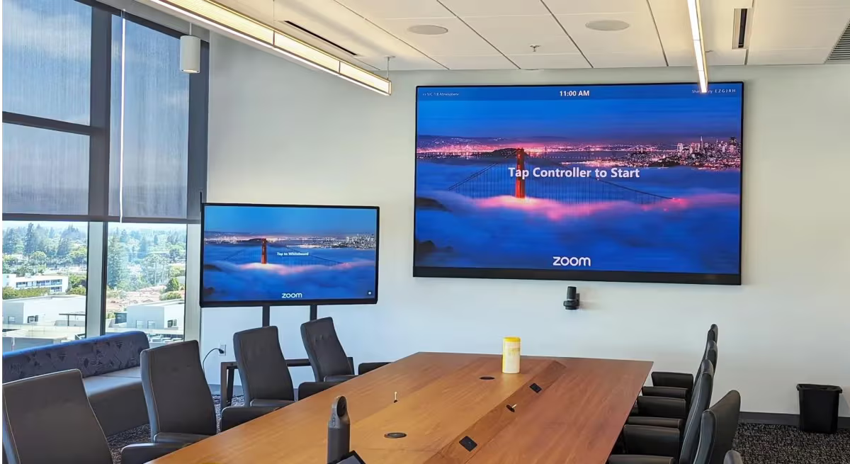 Conference room with large screens and a wooden table.