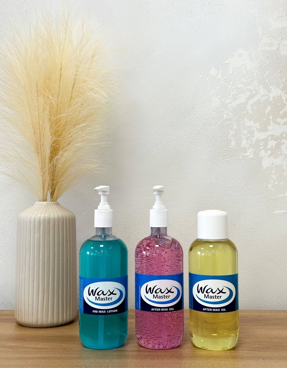 Three bottles of WAXX products next to a decorative vase.