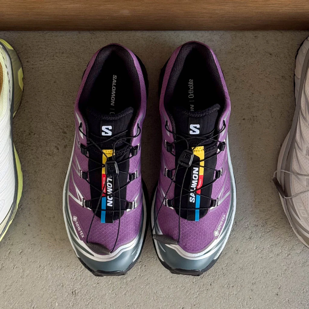 A pair of purple athletic shoes next to two other pairs.