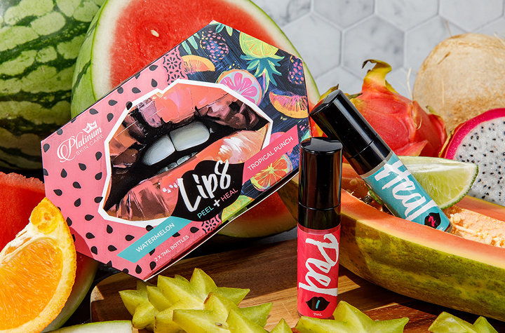 Colorful lip products displayed with fresh fruits in the background.