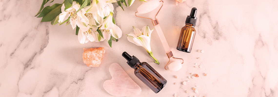 Two amber glass bottles alongside white flowers on a marble surface.