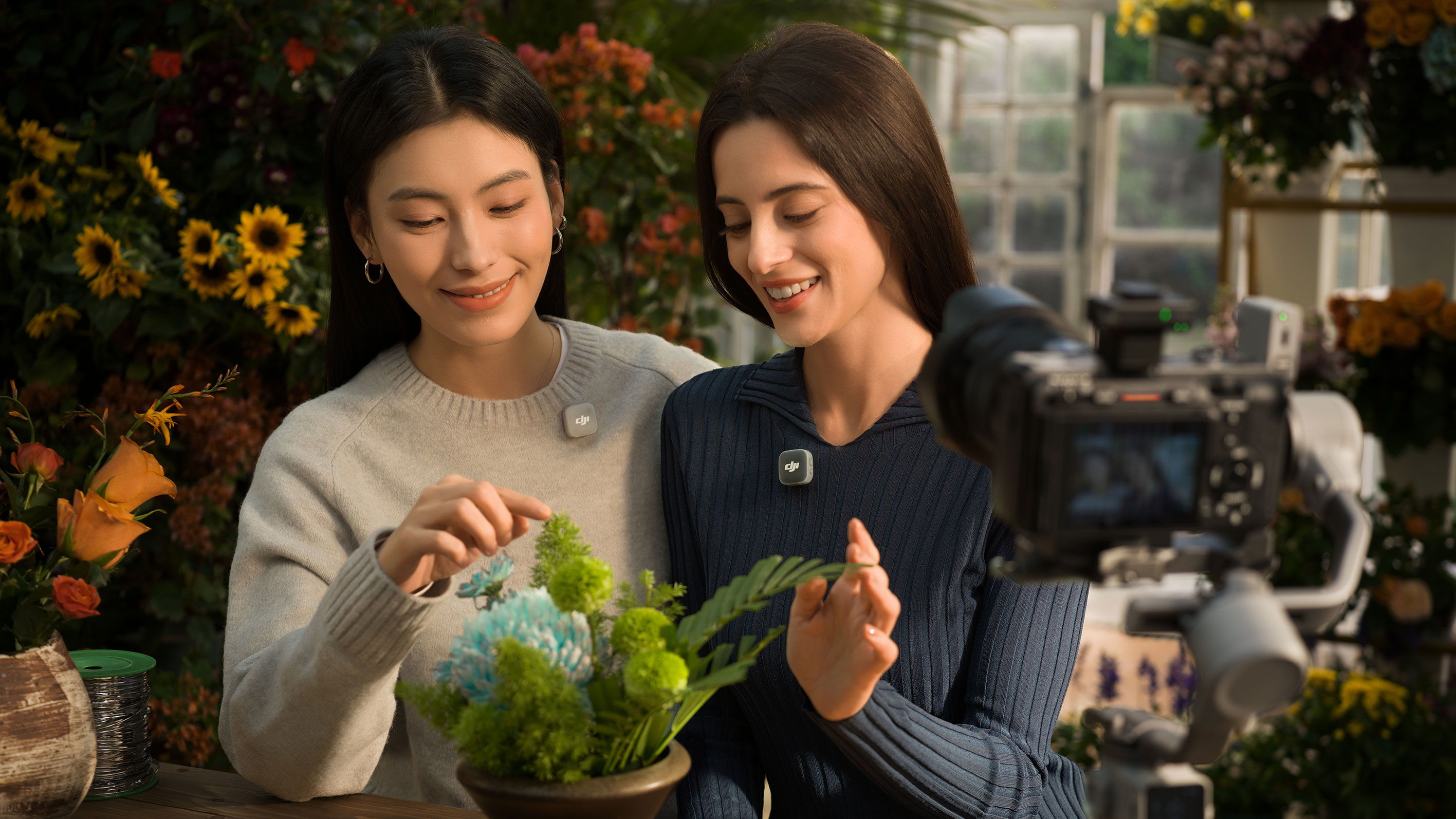 Two women joyfully arranging flowers in a floral shop while recording audio with DJI Mic Mini 2