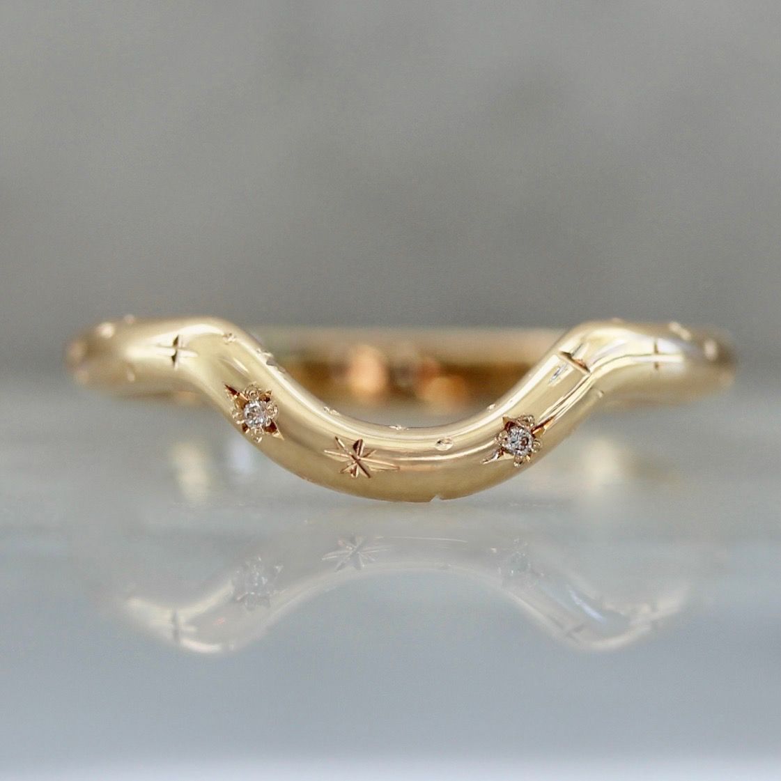 Curved wedding band hand-engraved with stars and star set diamonds