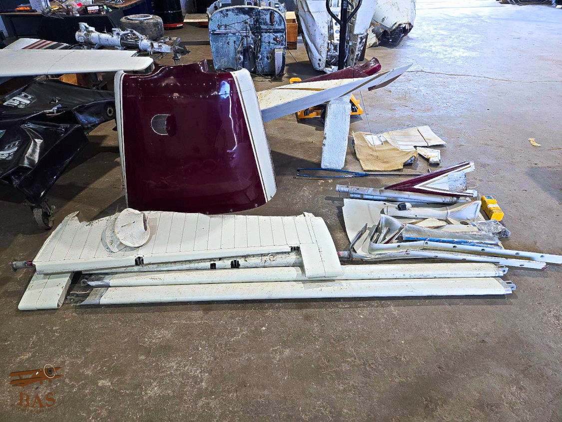 Aircraft parts and components scattered on a workshop floor.