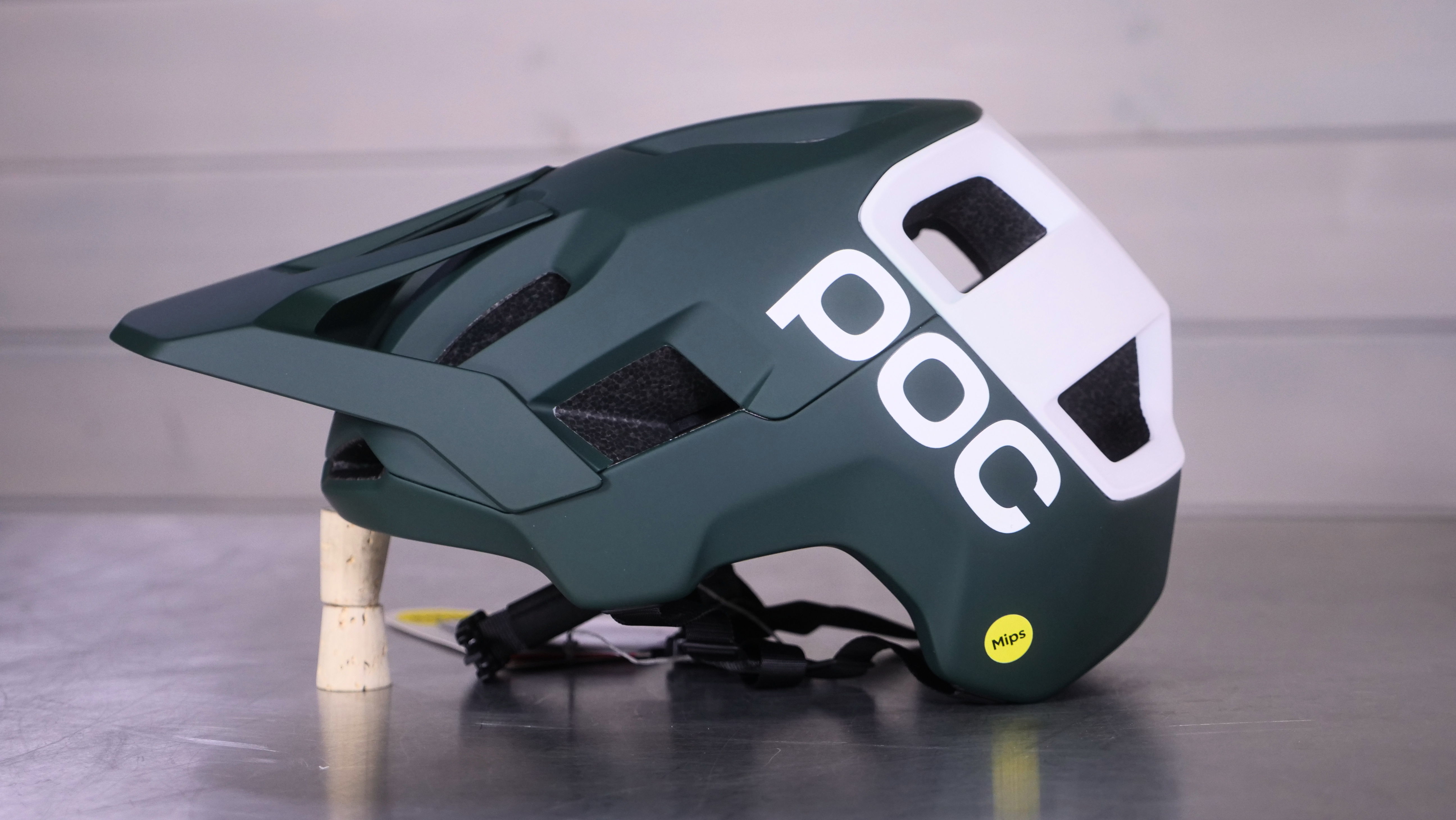 Green POC helmet shown from the side on a flat surface.