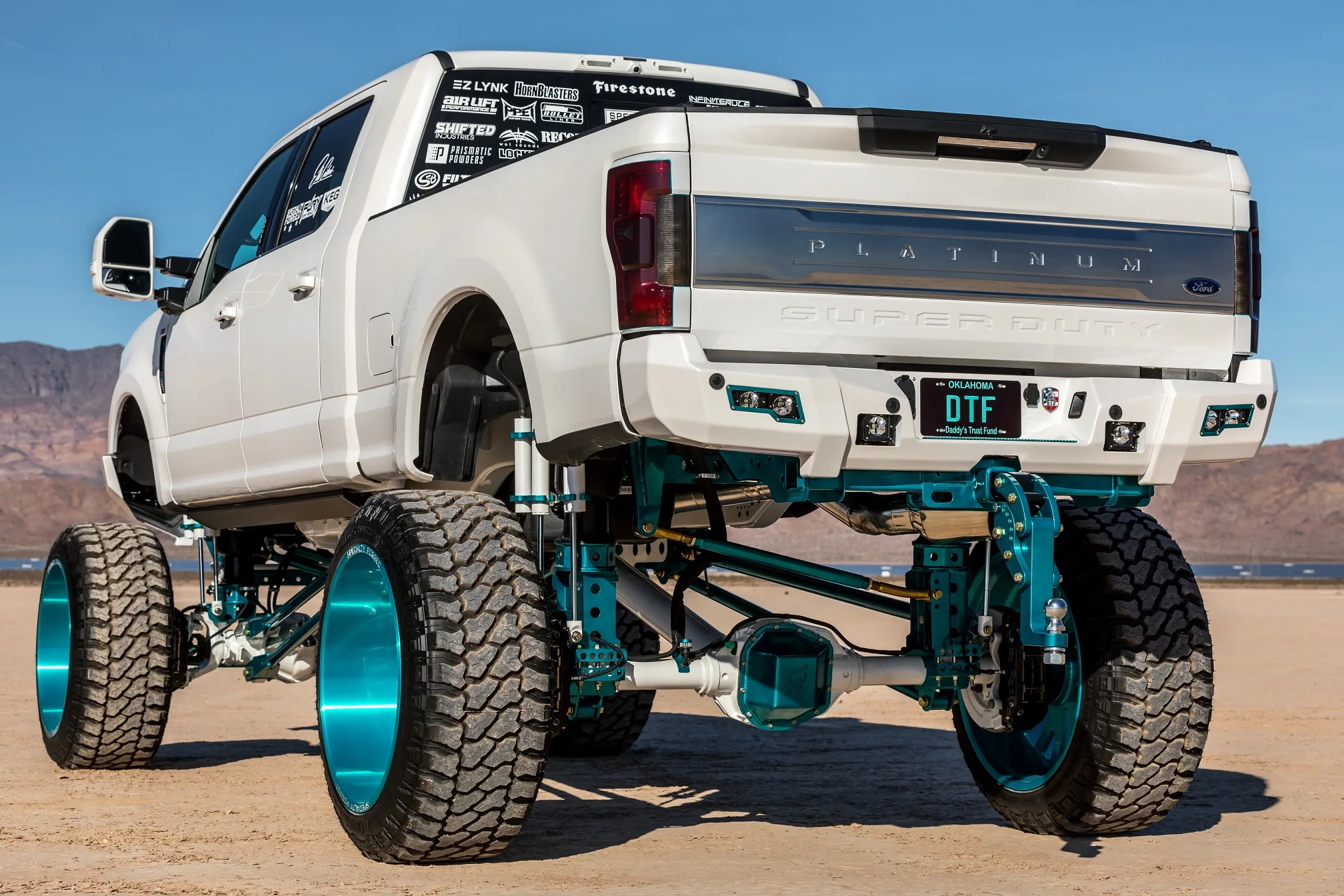 Rear three-quarter view of white Ford Super Duty lifted truck