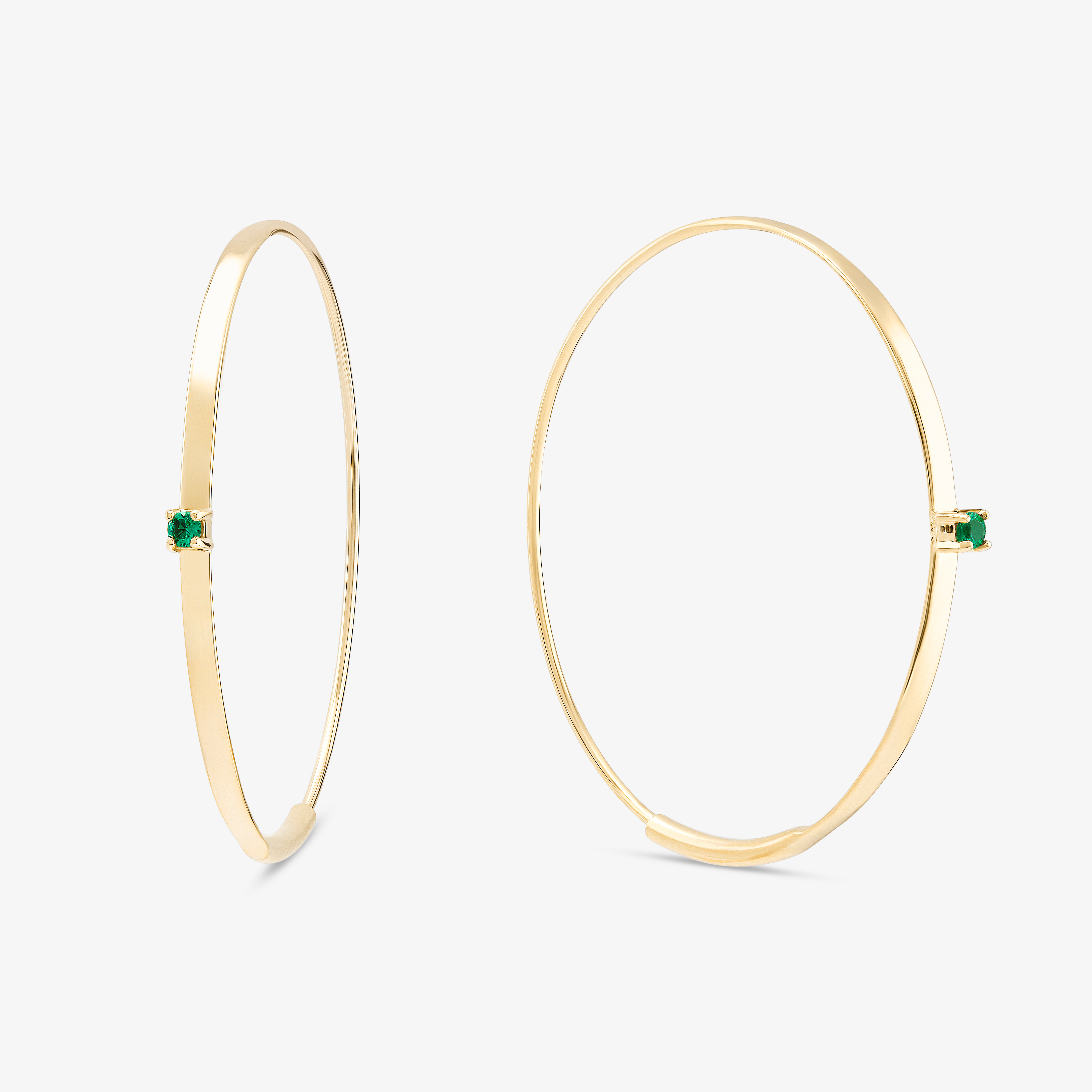 Gold hoop earrings with green gemstones.