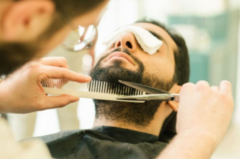 Barber trimming a guest's beard