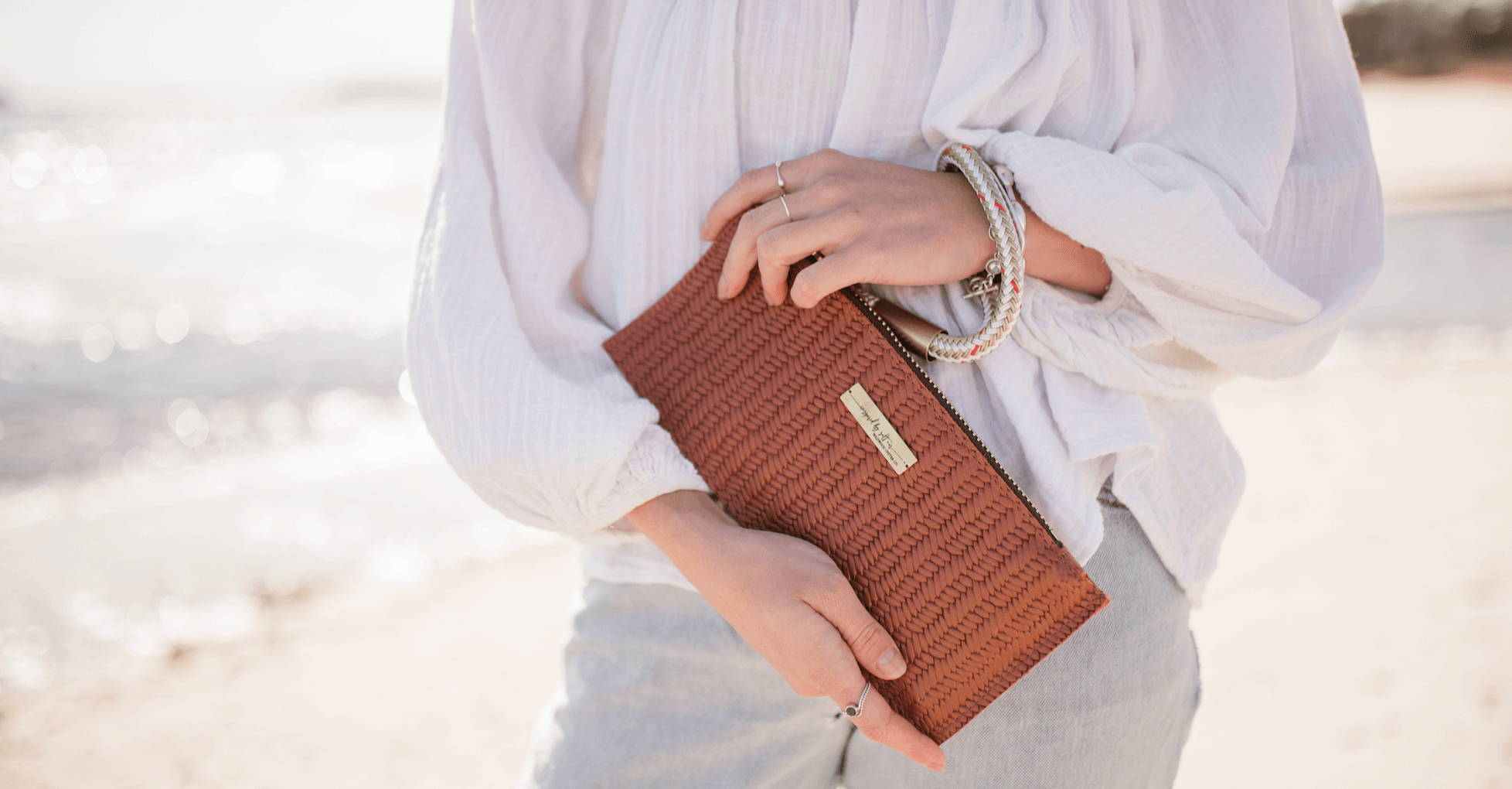 woman wearing a brown basketweave clutch at the beach