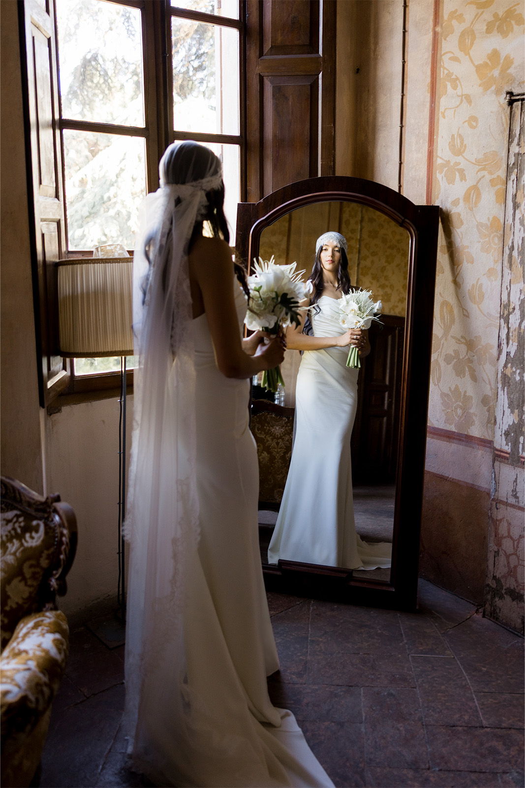 Bride in a wedding dress admiring herself in a mirror.
