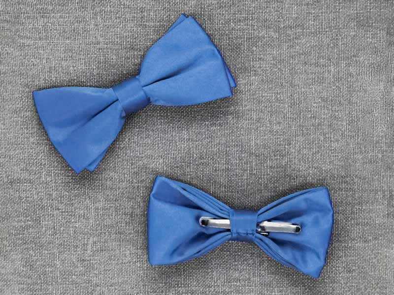 The front and back of two blue clip-on bow ties on a gray textured background
