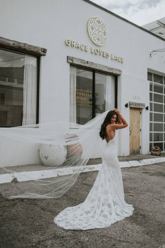 La novia lleva el vestido Rosa y el velo Henri fuera de la sala de exposiciones de Dallas Grace Loves Lace