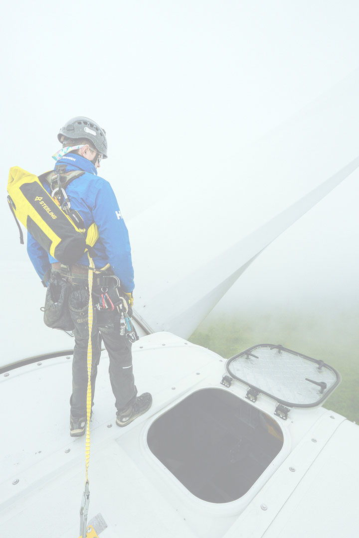 person standing on top of a wind turbine