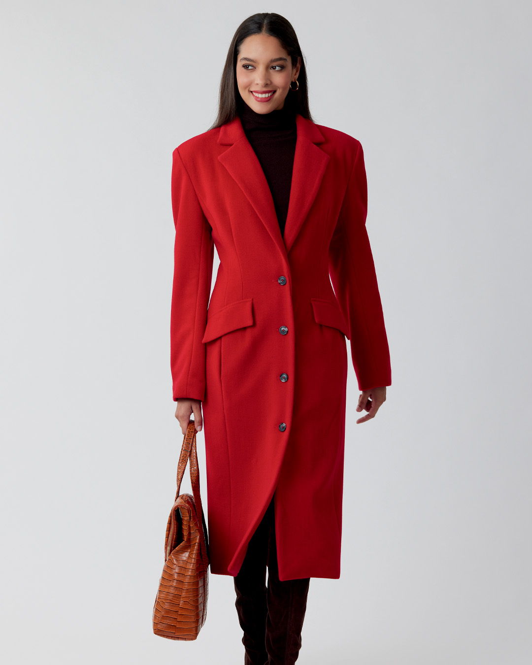 Woman in a red coat holding a brown handbag.