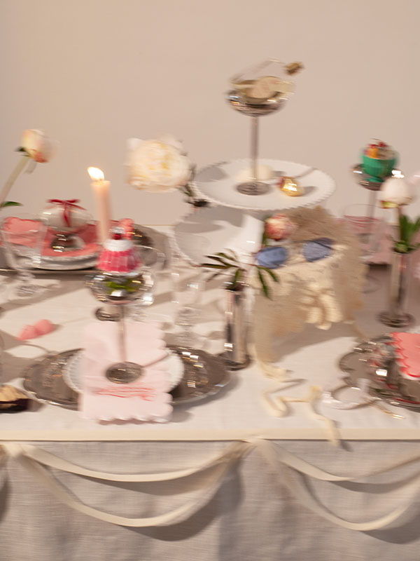 Decorative dessert table with various sweets and candles displayed on elegant stands.