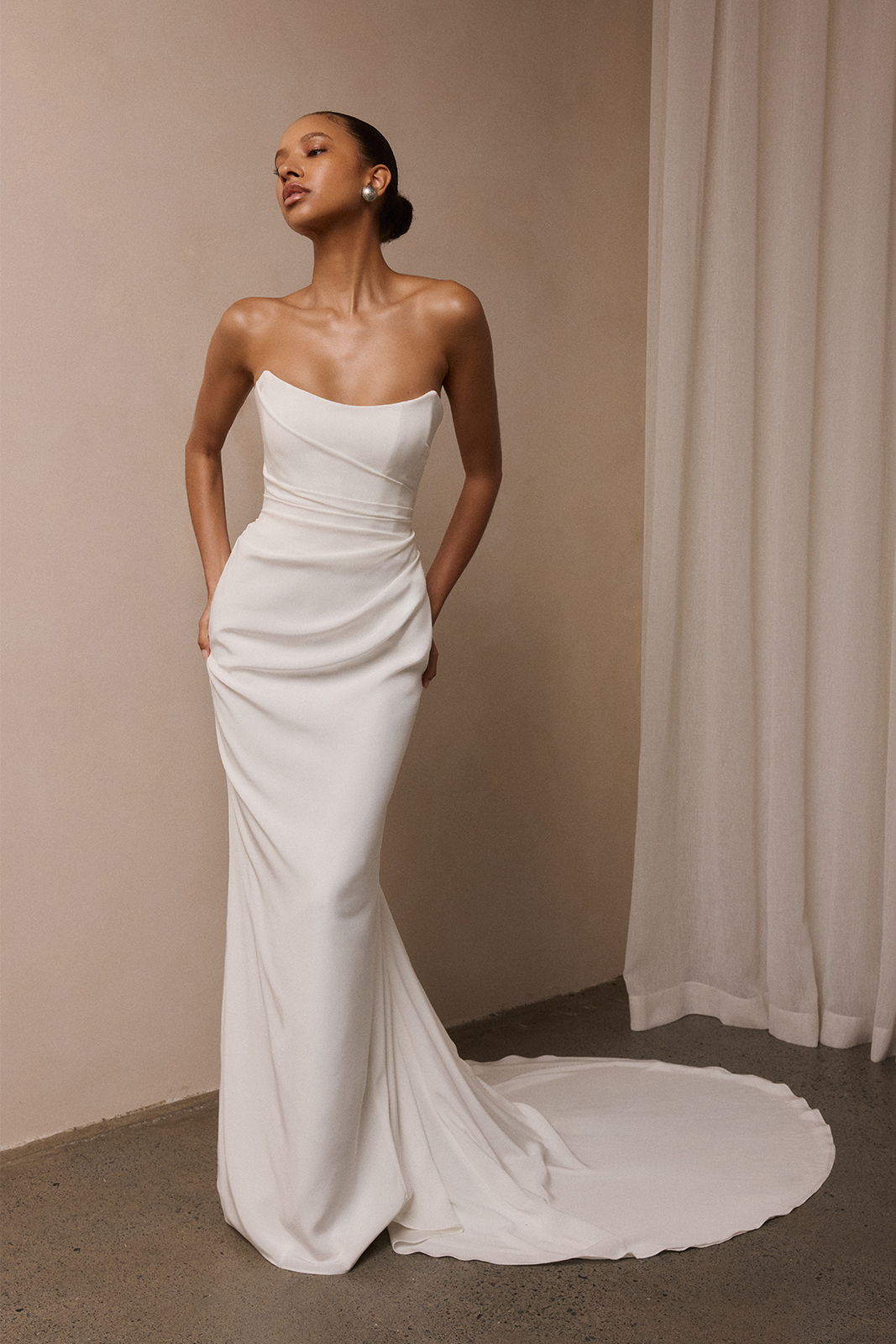 Model in a strapless white gown against a neutral backdrop.
