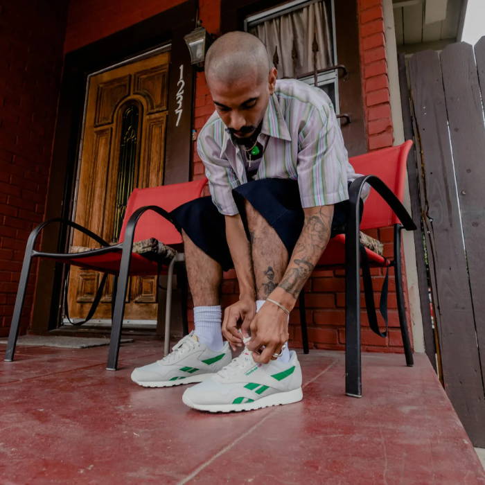 man tying reebok sneakers on front porch