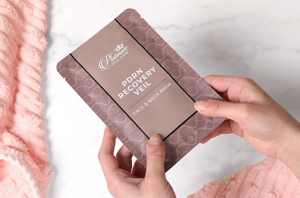 Person holding a decorative brown package on a marble surface.