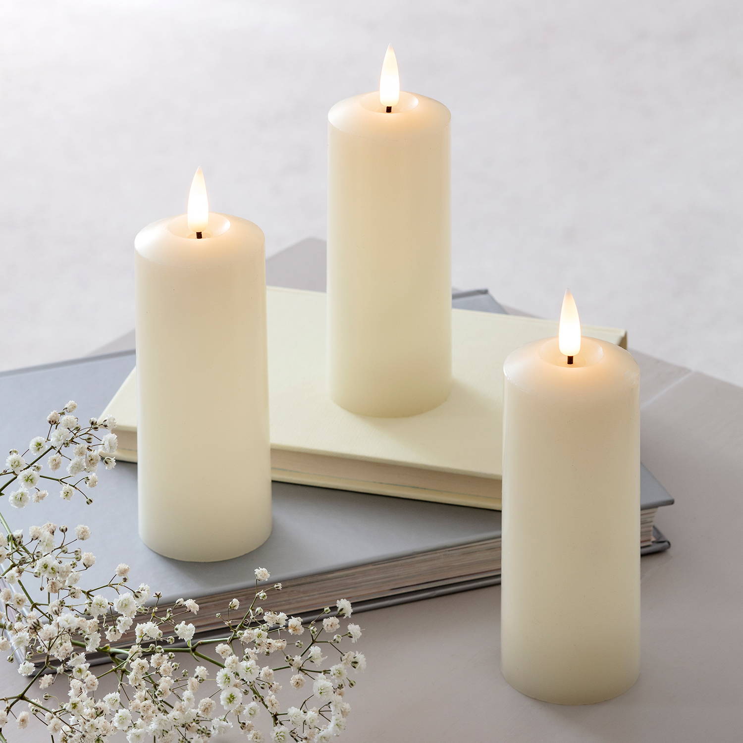 Slim ivory pillar candles illuminated on table top