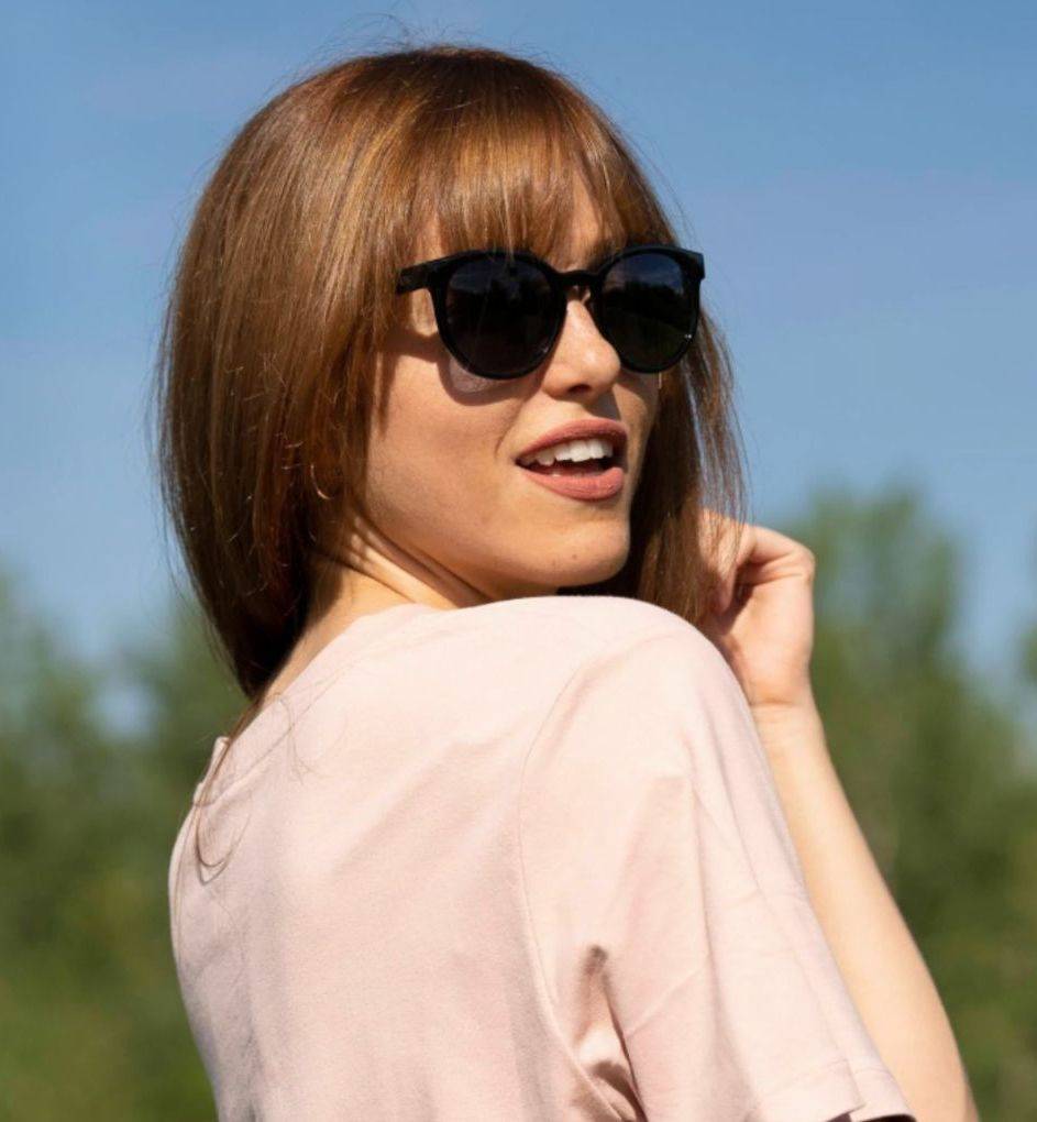 Woman with medium brown hair wearing Luxy black round sunglasses