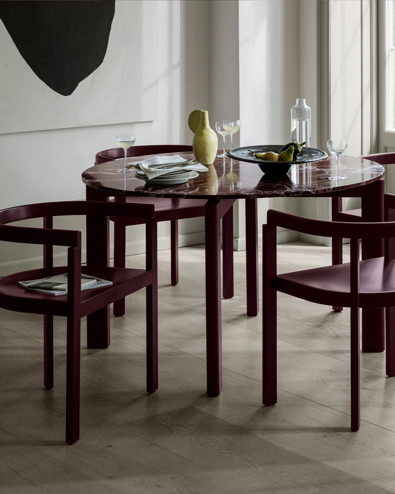 A modern After Series dining table set by Fritz Hansen with burgundy chairs and decorative items.