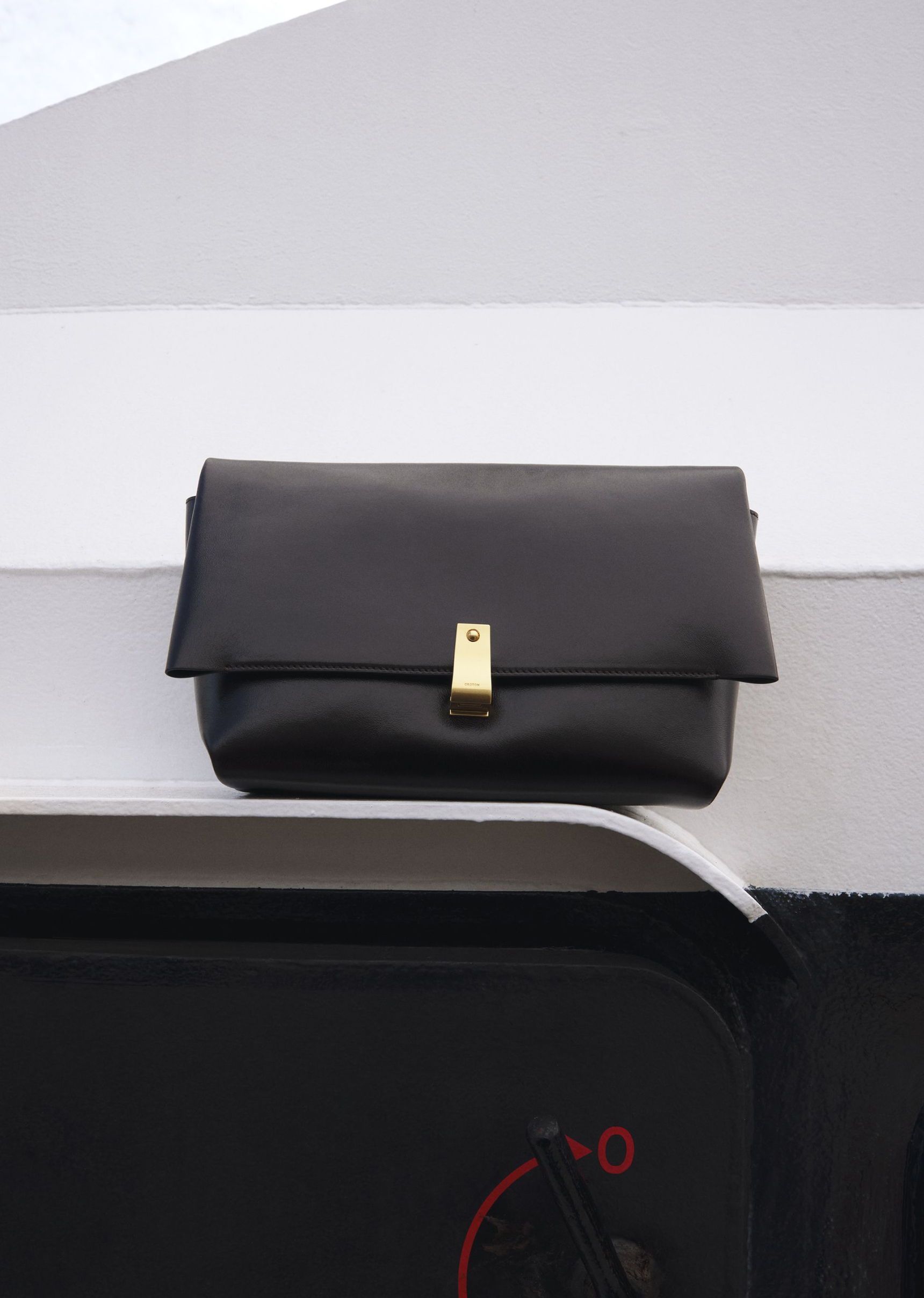 A black clutch bag resting on a white surface.