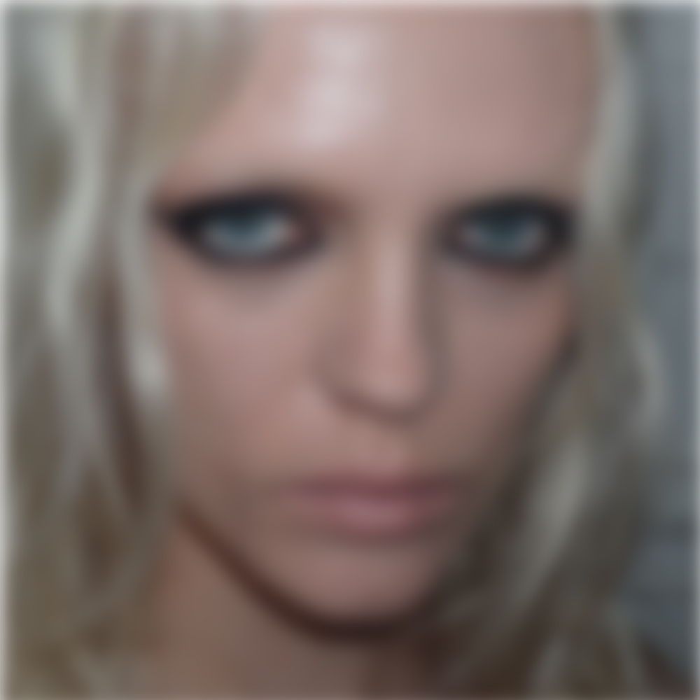 Blurred portrait of a person with light hair and striking blue eyes.