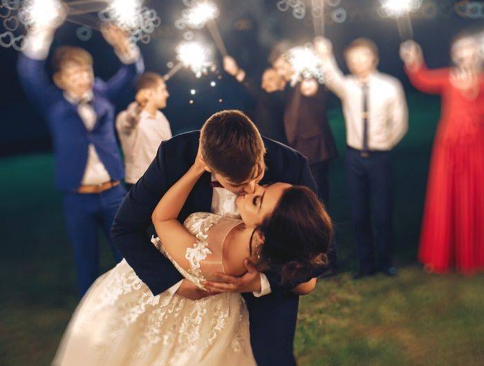 Bride and groom kissing outside at night