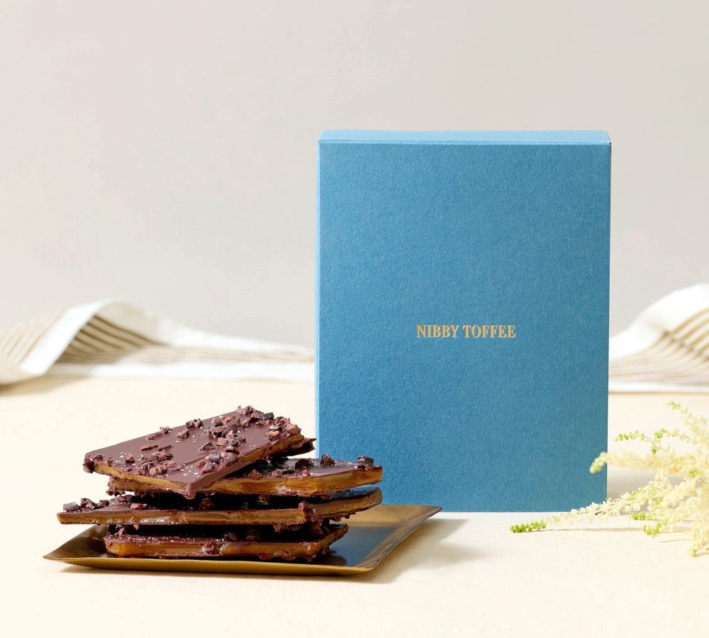 A blue box with cookies on a plate beside it.
